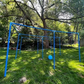 Large blue PVC game frame with 4 open top squares and 9 upright poles; on a grass playing area.