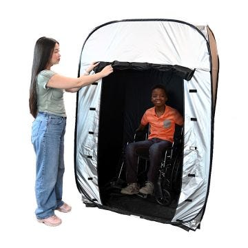 Gray black Enablemart Blackout Sensory tent with a person on wheelchair inside & another person standing outside; holding the entrance flap open.