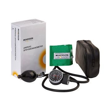 A green blood pressure cuff with the inflatable bulb; aneroid; black carrying case; and white box that the product arrives in.