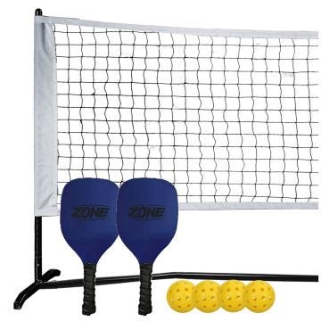 A portable net system with two blue pickleball paddles and four yellow perforated pickleballs.