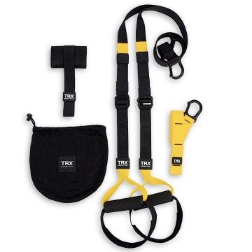 17381PS_00 - TRX Suspension Trainer set displayed on a white background, featuring black and yellow adjustable straps with foam handles, a door anchor, a mesh carrying bag, and a carabiner attachment for secure mounting.