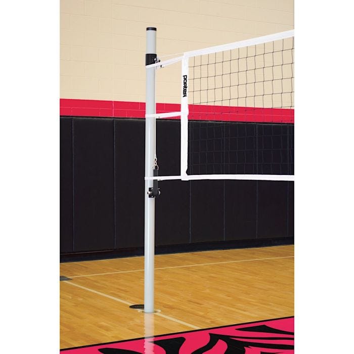 A close-up of a Porter volleyball net system installed in a gymnasium. The silver volleyball pole is anchored into the gym floor, supporting a taut white volleyball net with black mesh. The "Porter" logo is visible on the net. A close-up of a Porter volleyball net system installed in a gymnasium. The silver volleyball pole is anchored into the gym floor, supporting a taut white volleyball net with black mesh. The "Porter" logo is visible on the net.