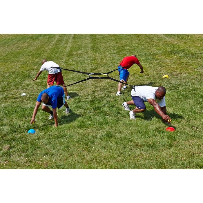 Four adult players secured in a 4-way harness. Each player is pulling in a different direction, attempting to grab a ball off of a cone. Four adult players secured in a 4-way harness. Each player is pulling in a different direction, attempting to grab a ball off of a cone.